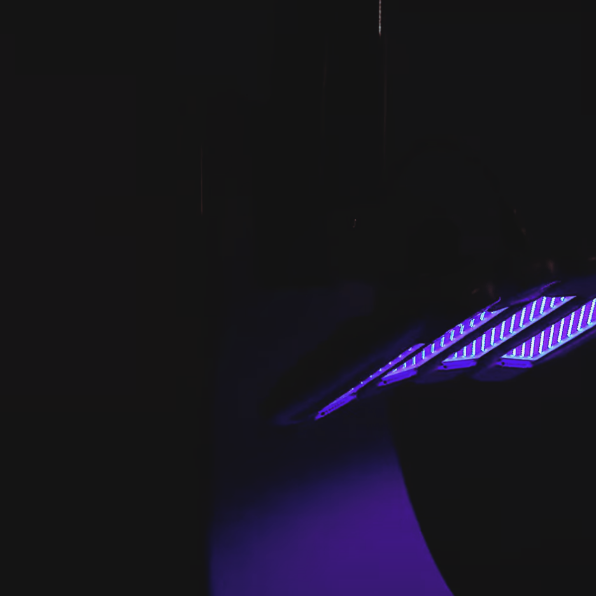 Dermalux LED phototherapy panel glowing blue in a darkened treatment room