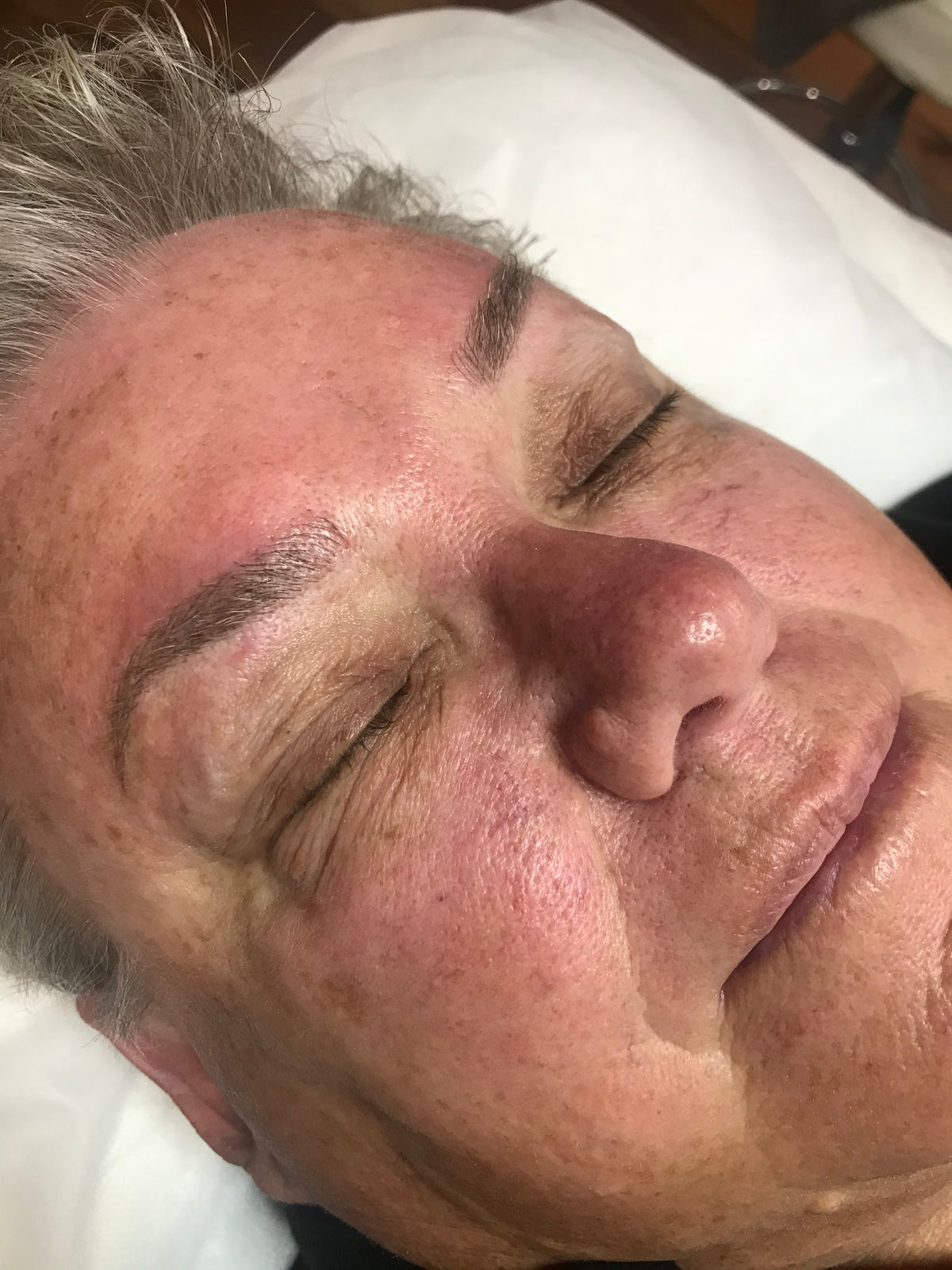 The same mature client after cosmetic tattooing, with defined brows restoring shape