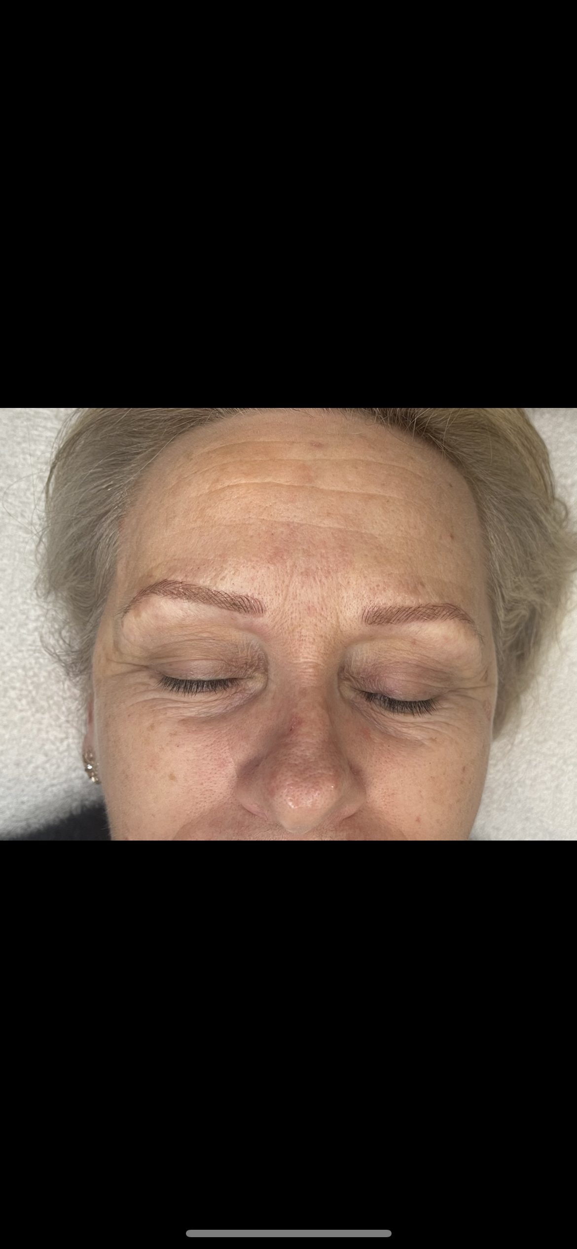 Healed microblading result showing warm-toned brows with defined arches