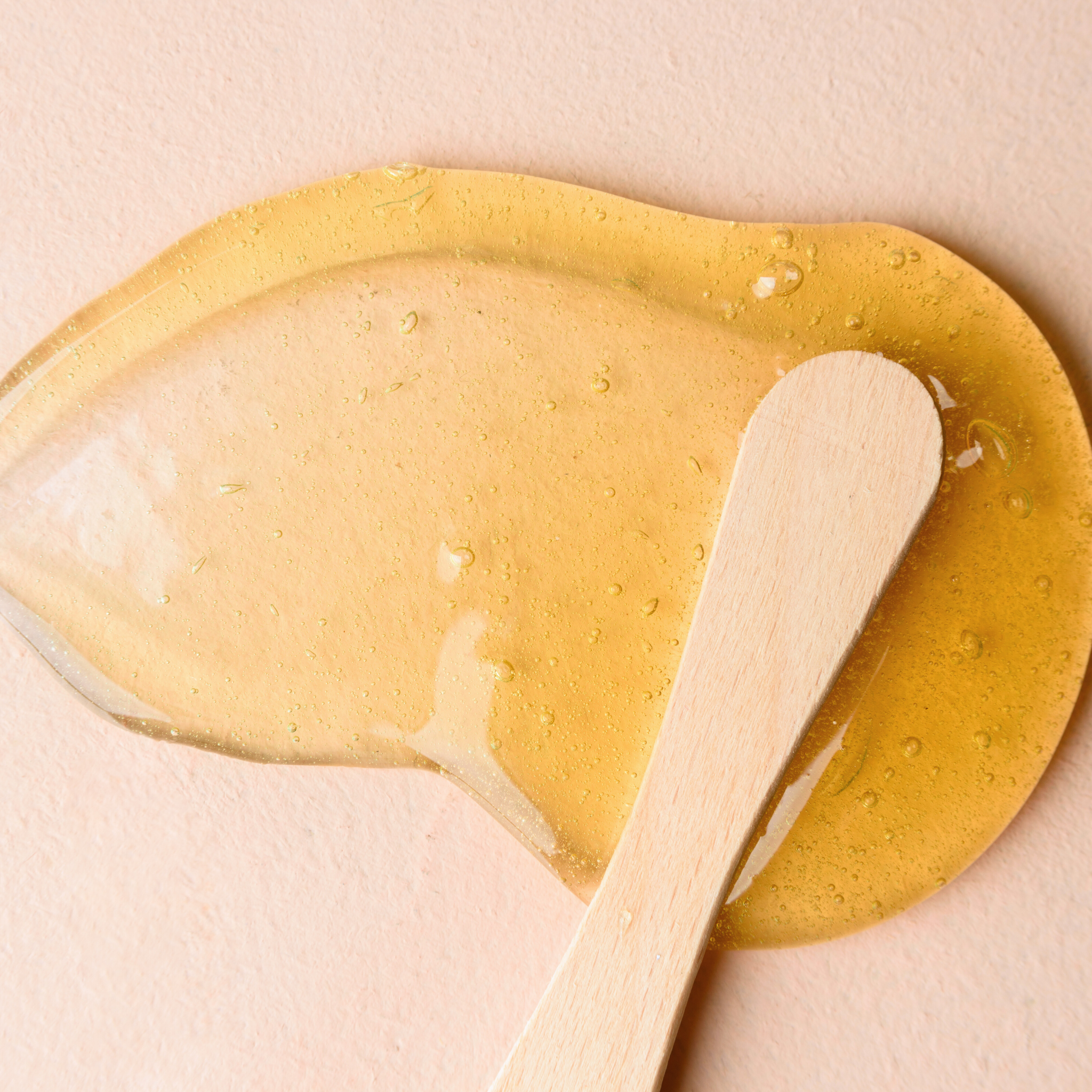 Close-up of golden honey wax and spatula used in professional waxing treatments at Amavi Beauty Lounge in Brisbane